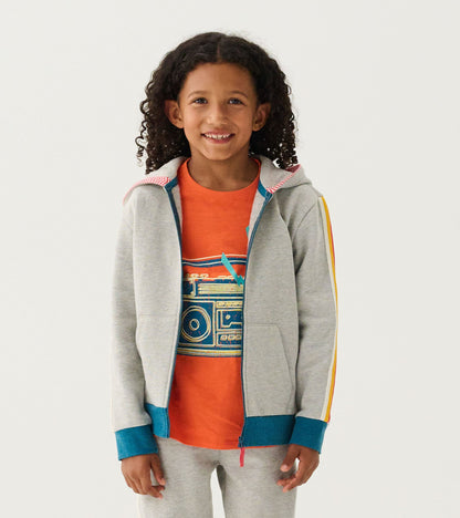 Grey zip-up hoodie with colorful accents, featuring a hood and front pockets, worn over an orange graphic t-shirt.