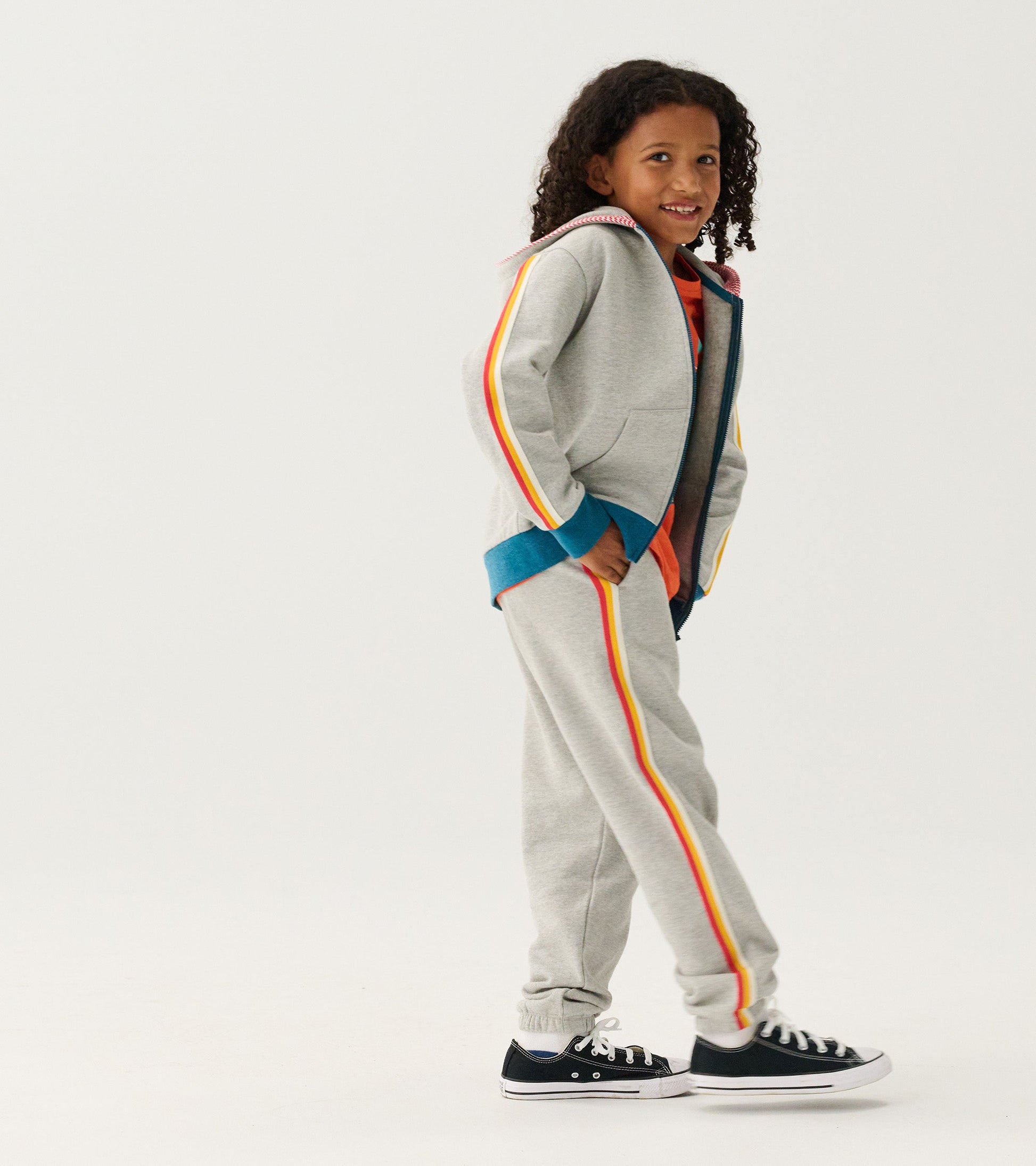 Grey zip-up hoodie with colorful side stripes, worn by a child, featuring a hood and front pockets.