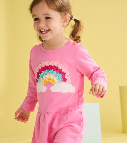 Pink long-sleeve toddler dress with rainbow and cloud graphic, front view, flounce skirt hem