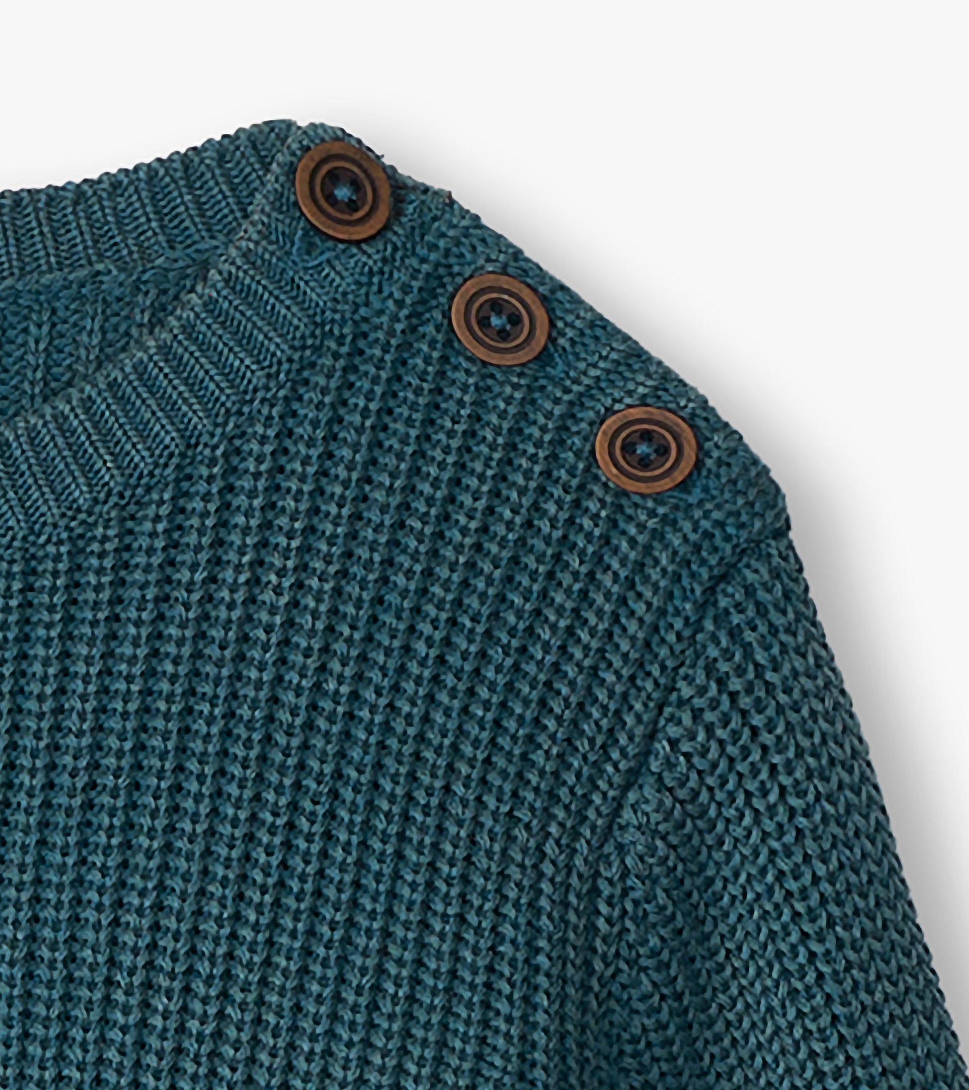 Close-up of the blue sweater shoulder with three brown buttons at the button neck and ribbed knit texture