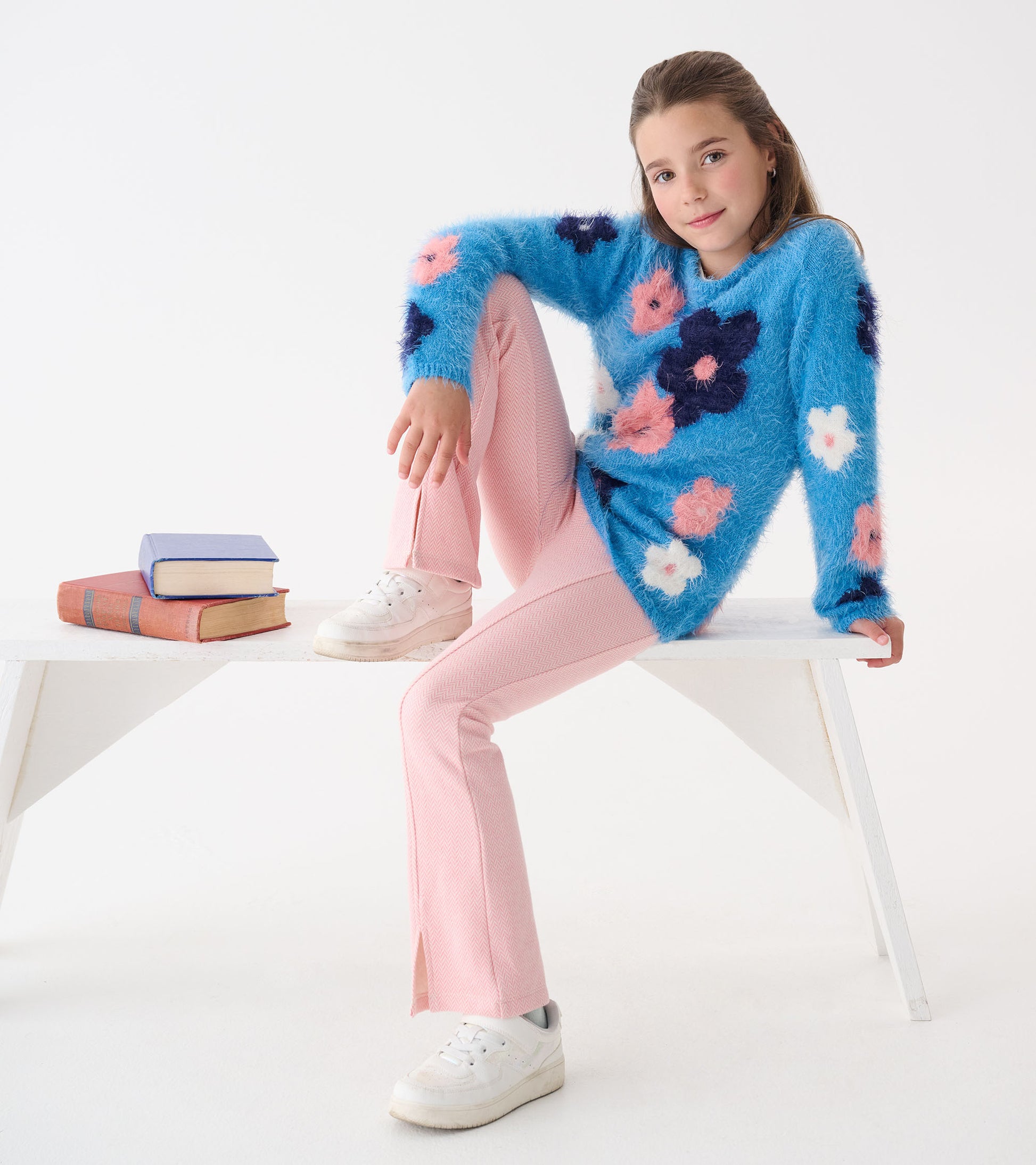 Furry blue sweater with colorful floral pattern, paired with pink pants and white sneakers, styled casually.