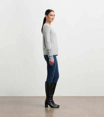 Grey melange sweater with patterned cuffs, featuring a relaxed fit, styled with blue jeans and knee-high black boots.