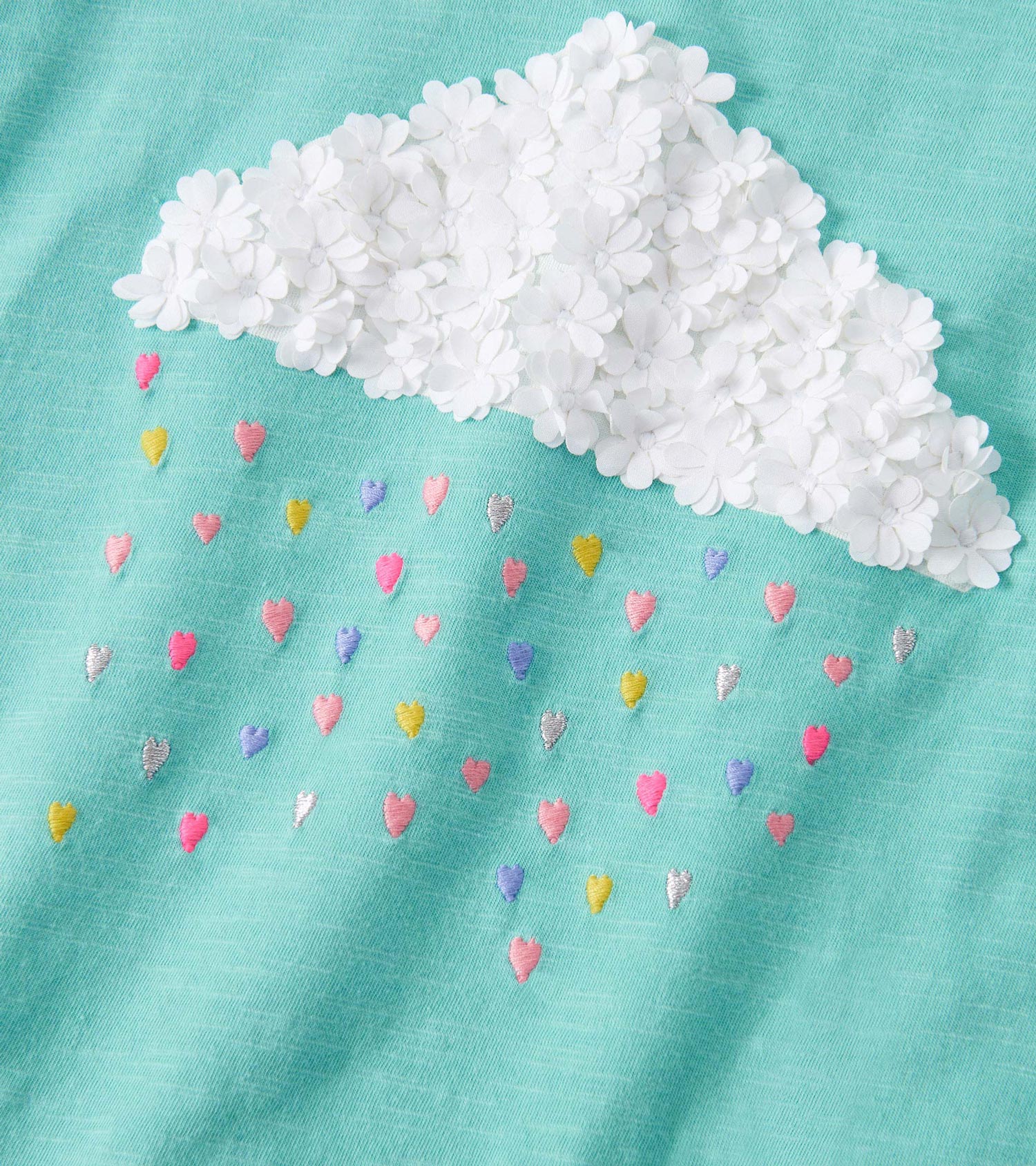 Mint green graphic tee featuring a fluffy white cloud and colorful embroidered hearts. Puff sleeves add a playful touch.