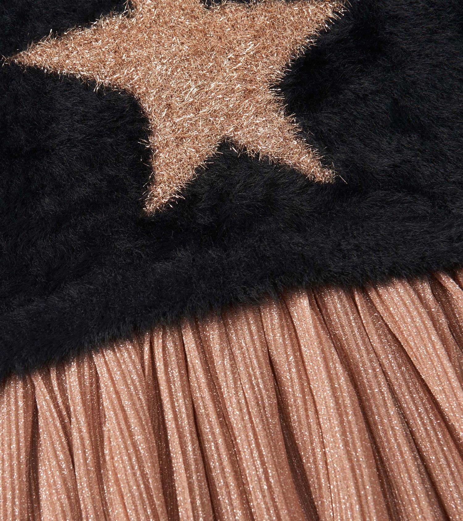 Black top with a gold star design and a pleated, shimmery rose gold skirt.
