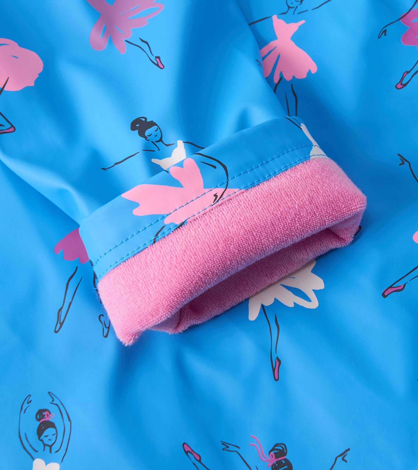 Blue rain jacket featuring ballet dancer prints, with a pink fleece-lined cuff for added comfort.