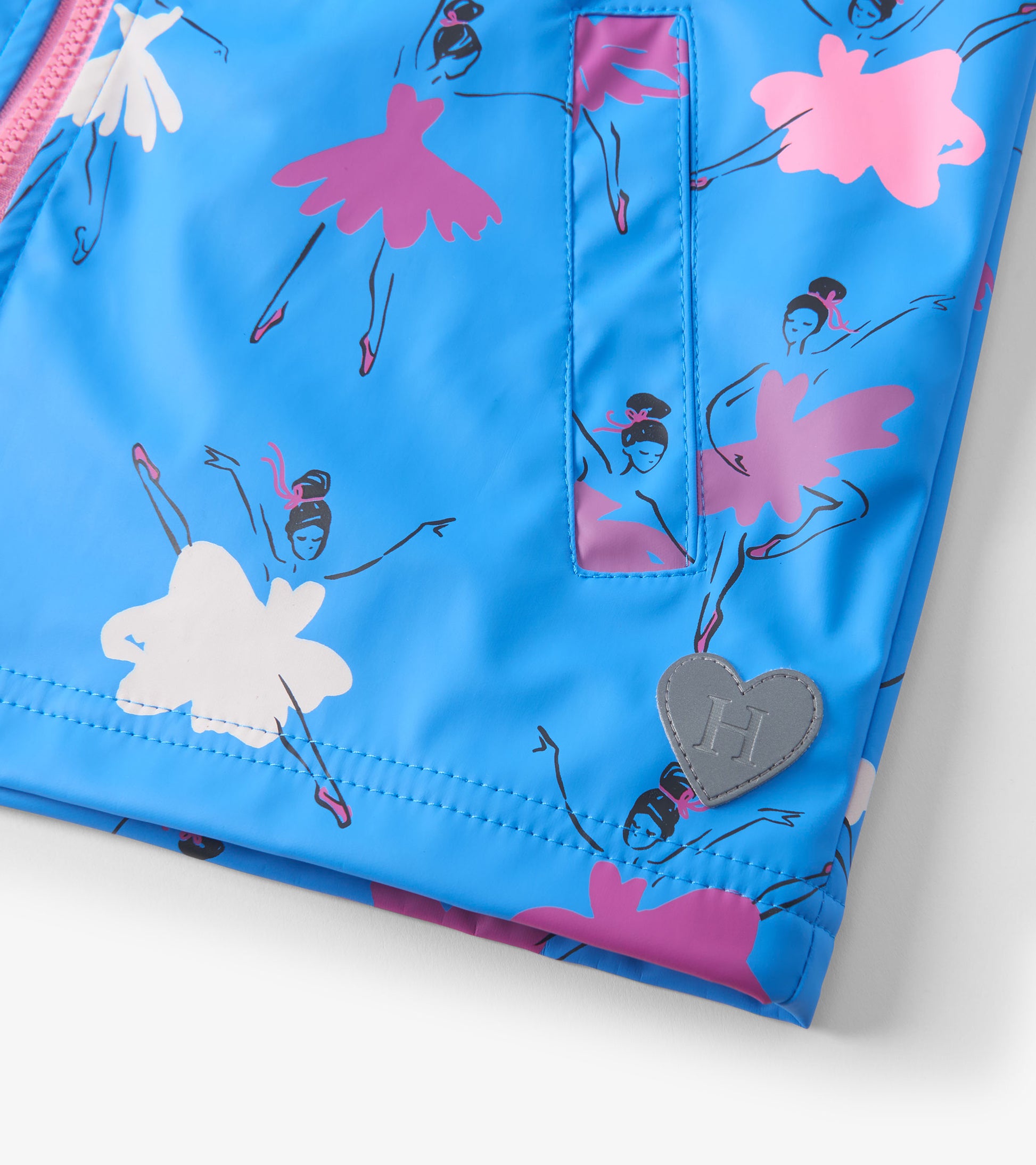 Bright blue rain jacket featuring colorful ballet dancer prints and a heart-shaped logo patch. Zip-up design.