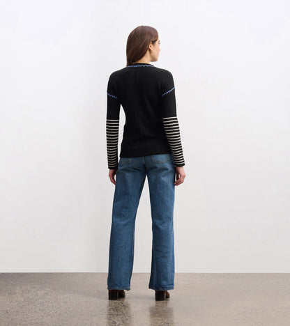Black sweater with striped sleeves, fitted body, and a round neckline, worn with blue jeans, viewed from the back.
