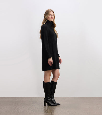 Black swing sweater dress with a high neckline and long sleeves, styled with knee-high black boots.
