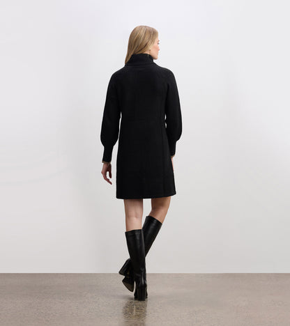 Black swing sweater dress with a high collar and long sleeves, styled with knee-high black boots.