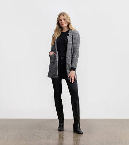 Cozy black check open blazer with pockets, styled over a black top and paired with black jeans and knee-high boots.