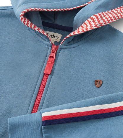 Blue zip-up hoodie featuring a red zipper, striped hood lining, and a small emblem on the chest.
