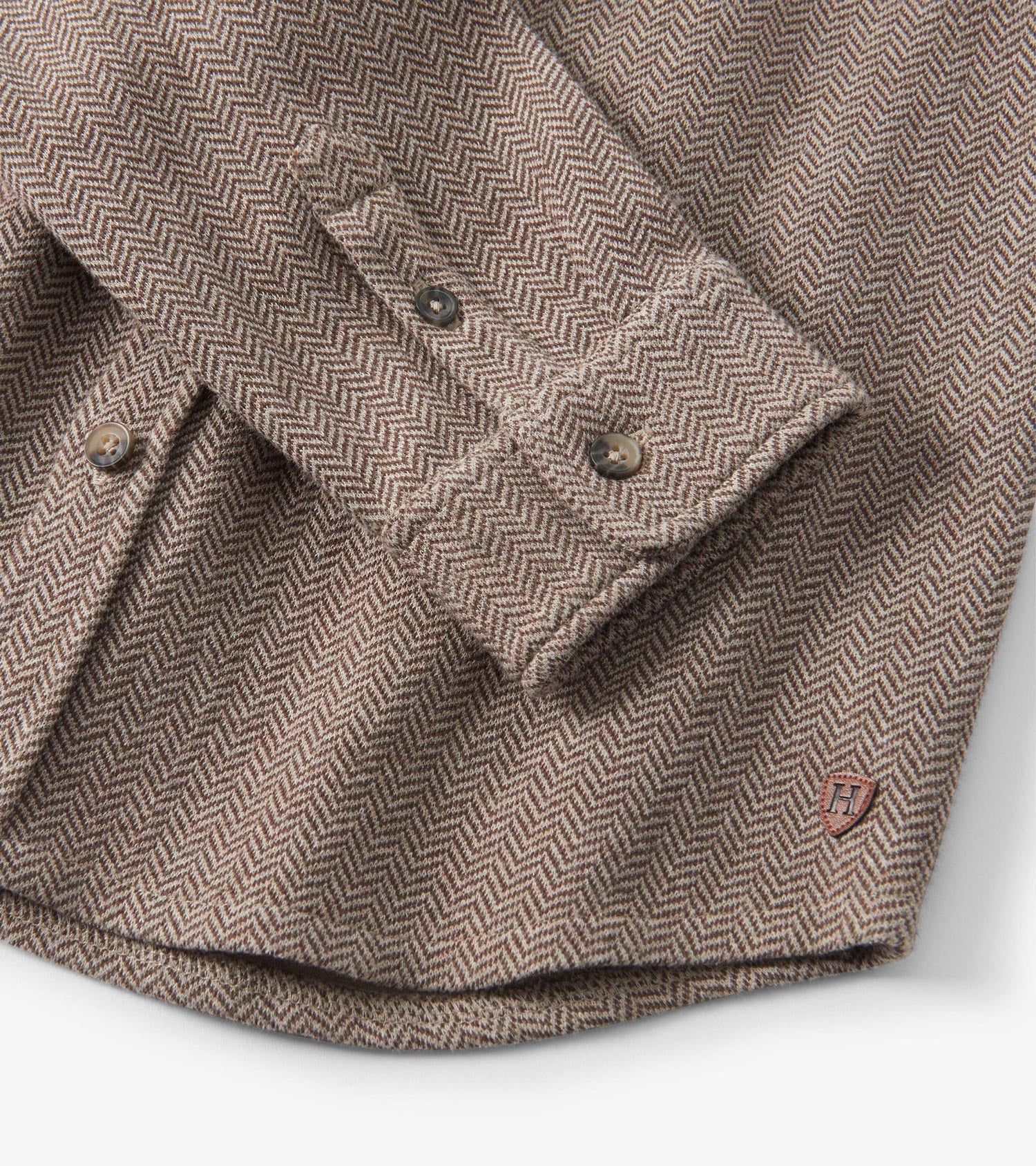Brown herringbone button-down shirt with a collar and button cuffs, featuring a small logo patch on the hem.
