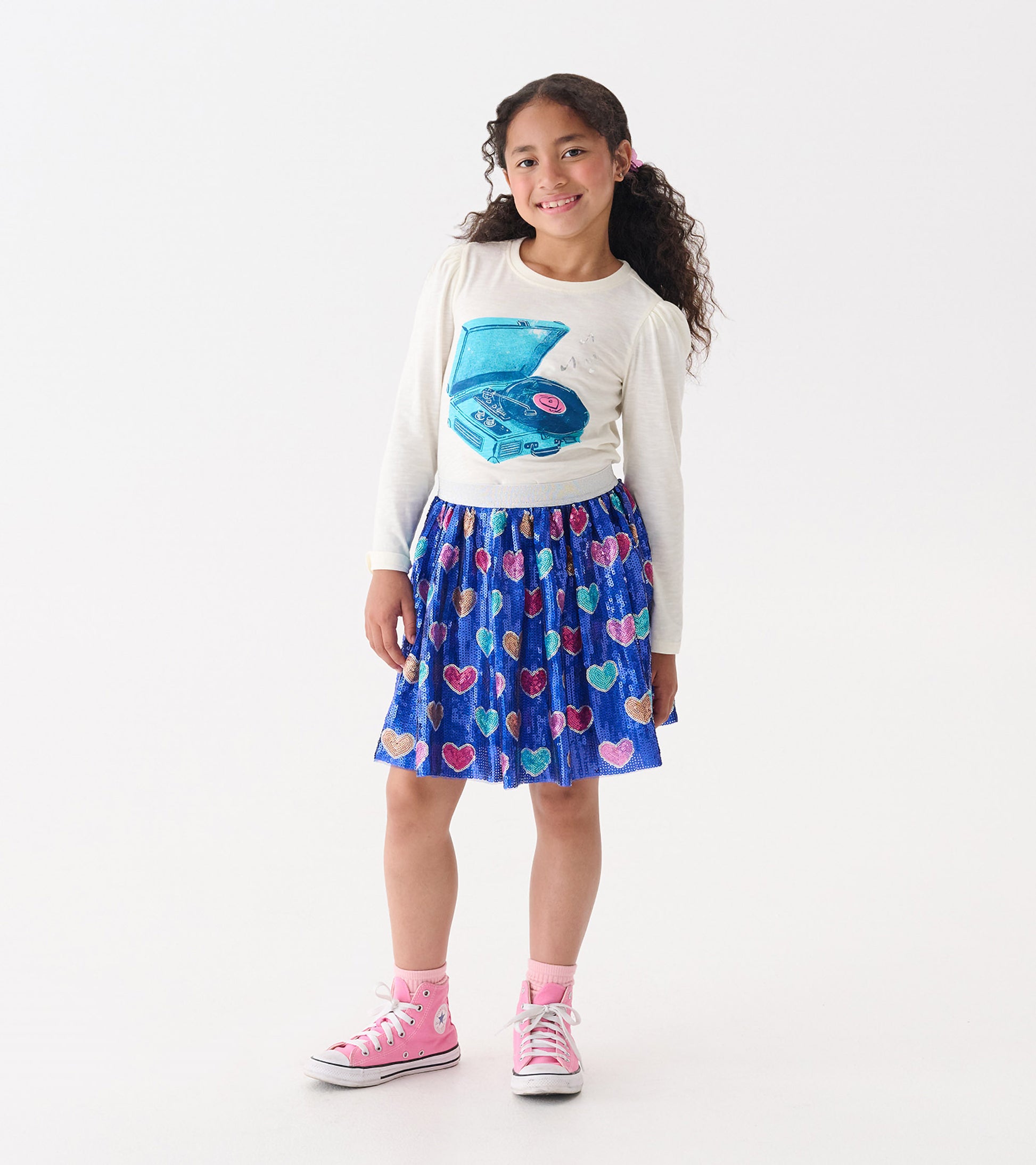 Cream long-sleeve tee with a record player graphic, paired with a blue skirt featuring colorful heart patterns.