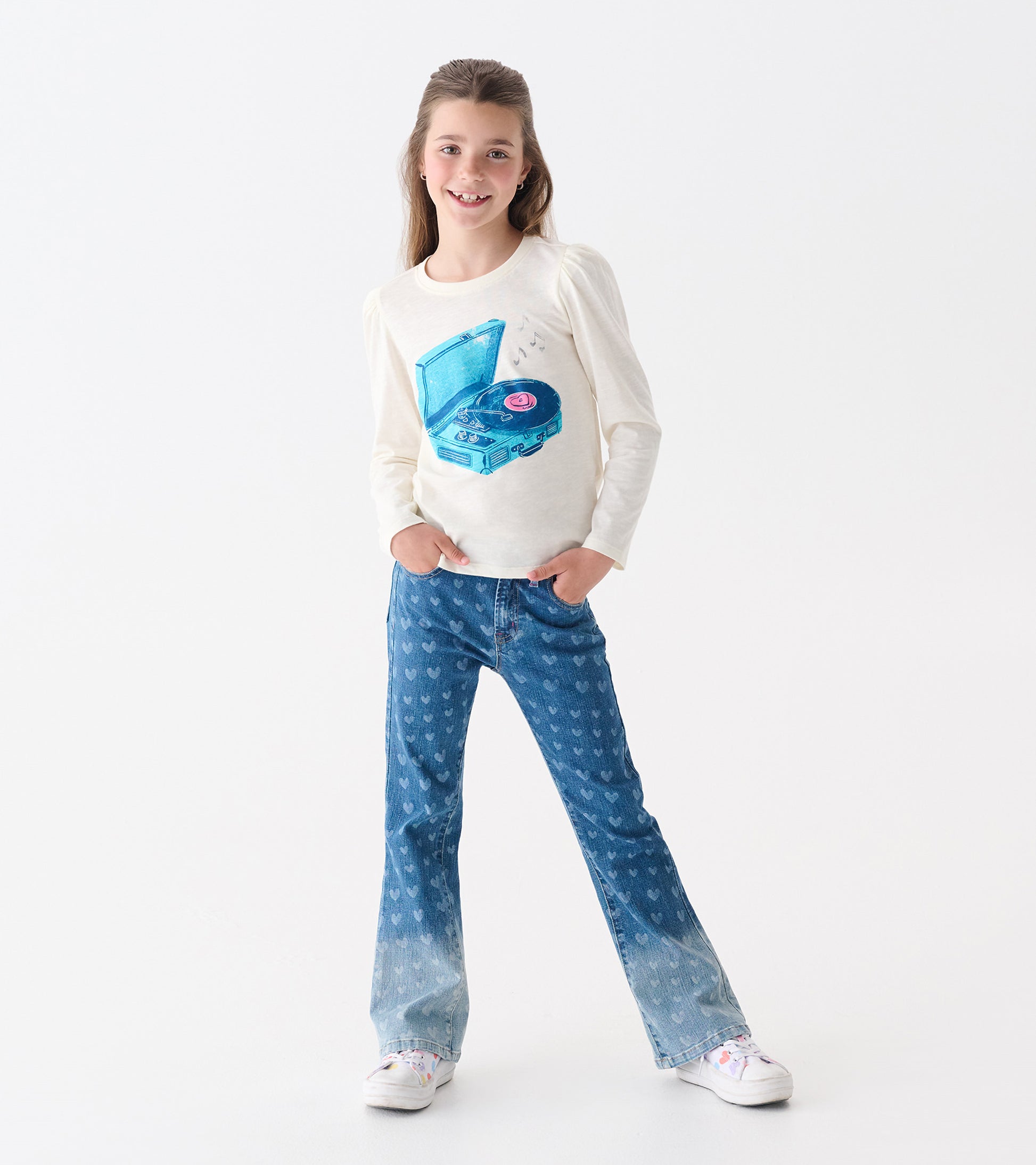Cream long-sleeve tee with puff sleeves featuring a blue graphic of a record player. Paired with heart-patterned jeans.