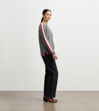 Charcoal sweater with pink and white contrast trim, featuring a relaxed fit and side slits, worn with black pants.