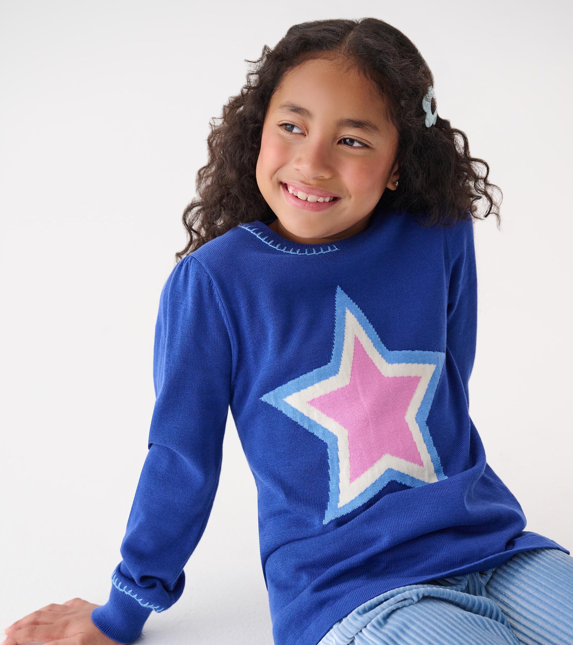 Blue pullover sweater featuring a large star design in pink and light blue, perfect for casual wear.