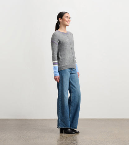Charcoal melange sweater with colorful striped sleeves, paired with wide-leg jeans, shown from the side.