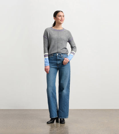 Charcoal melange sweater with colorful striped sleeves, worn with high-waisted jeans and heeled boots.