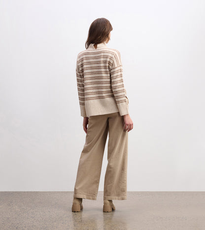 Mock neck sweater in camel with double stripes, featuring a relaxed fit and ribbed hem, styled with wide-leg pants.