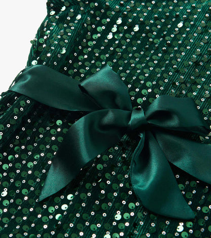 Green velvet dress adorned with sequins, featuring a large satin bow at the waist.