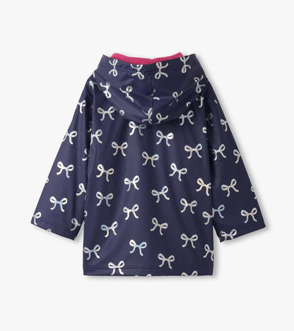 Navy rain jacket featuring a pattern of shiny silver bows, with a pink-lined hood and long sleeves.
