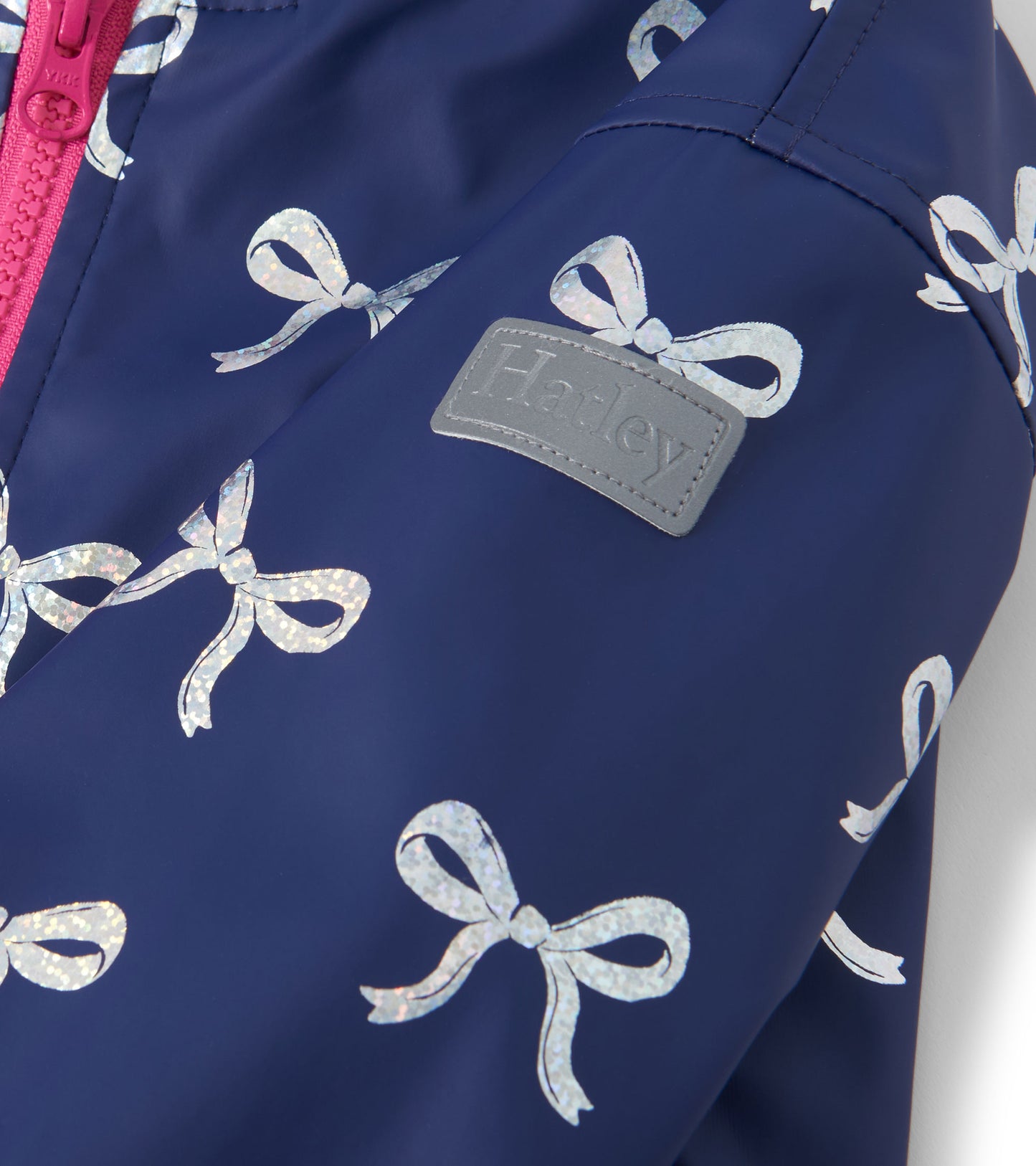 Navy rain jacket featuring silver ribbon patterns and a pink zipper, designed for girls.