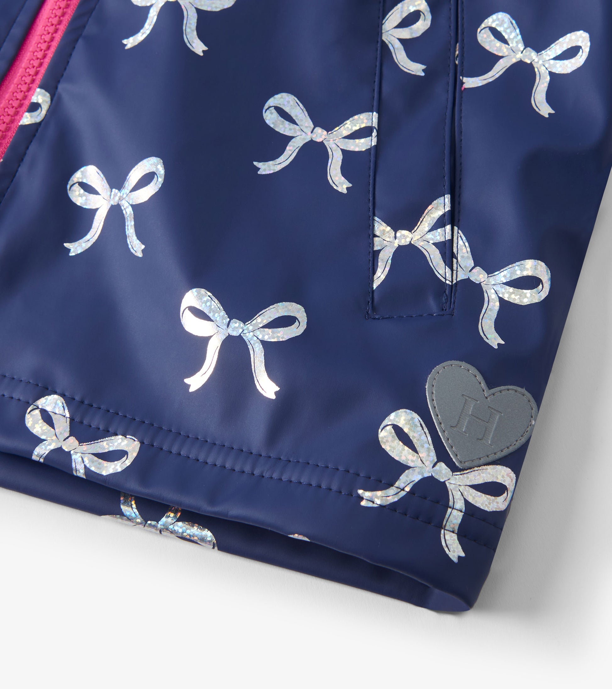 Navy rain jacket featuring shiny silver ribbon patterns and a heart logo patch, ideal for girls.