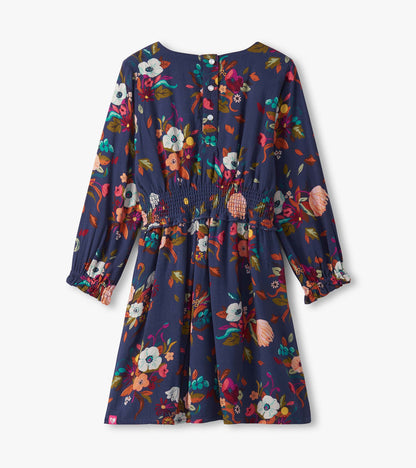 Navy blue floral dress with long sleeves, smocked waist, and a flared skirt, suitable for special events.