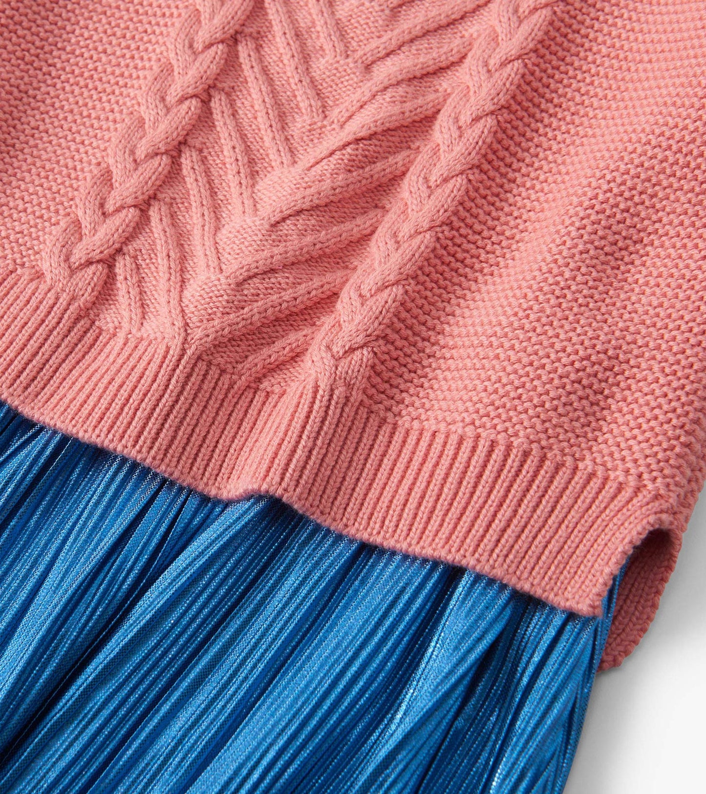 Flamingo pink knit top with braided texture, paired with a pleated blue skirt.