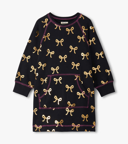 Black sweater dress featuring gold bow patterns and a front pocket, with purple stitching details. Available in multiple siz…