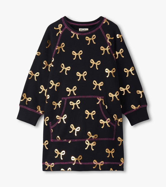 Black sweater dress featuring gold bow patterns and a front pocket, with purple stitching details. Available in multiple siz…