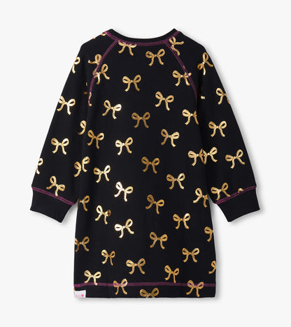 Black sweater dress featuring gold bow patterns and long sleeves, with a round neckline and purple stitching details.