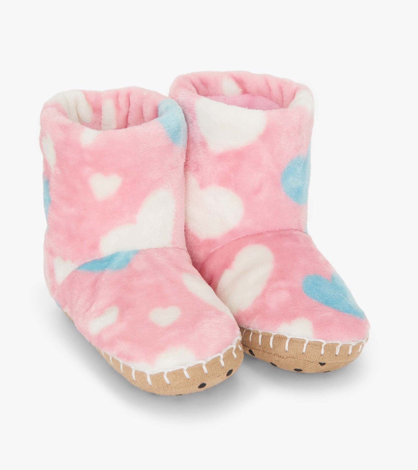 Pink fuzzy fleece slippers with white and blue heart patterns, featuring a soft lining and a textured sole.