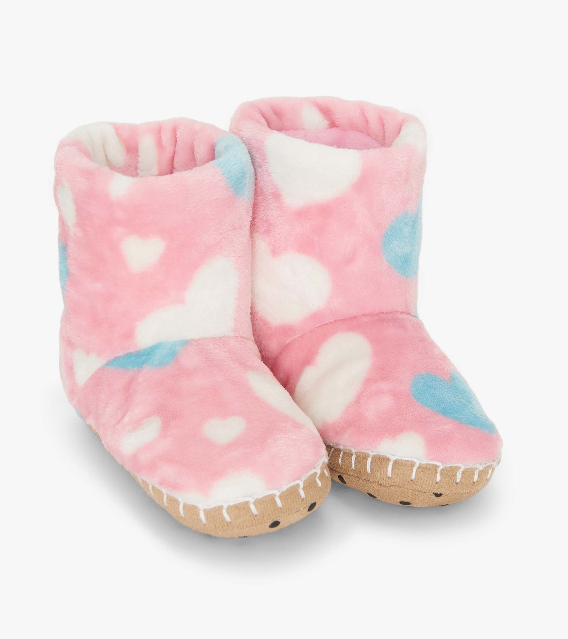 Pink fuzzy fleece slippers with white and blue heart patterns, featuring a soft lining and a textured sole.