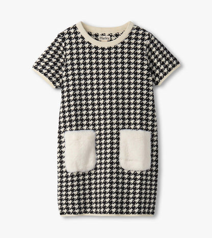 Black and white houndstooth sweater dress featuring faux fur pockets and a ribbed neckline. Short sleeves, casual fit.