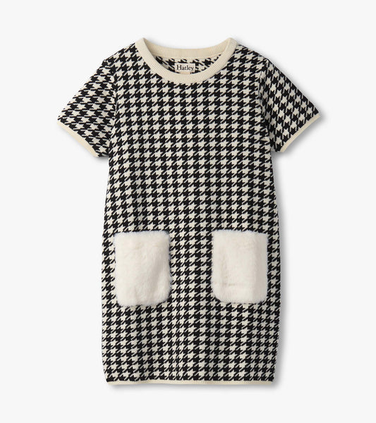 Black and white houndstooth sweater dress featuring faux fur pockets and a ribbed neckline. Short sleeves, casual fit.