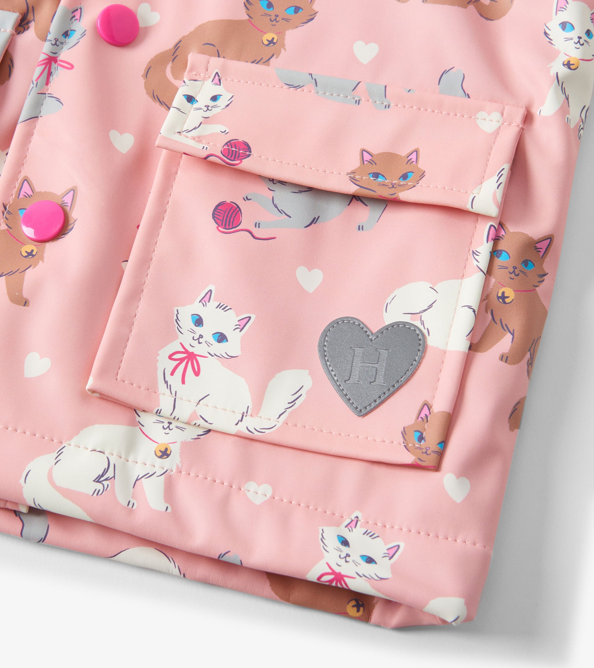 Pink rain jacket featuring playful kitty illustrations and heart patterns, with button closures and a front pocket.