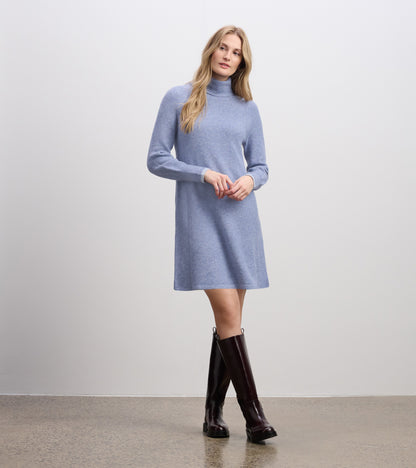 Light denim sweater dress with a high neck and long sleeves, styled with knee-high brown boots.