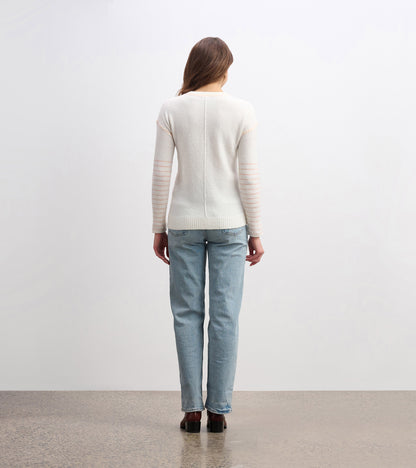Cream sweater with striped sleeves, fitted shape, and ribbed hem, shown from the back with light blue jeans.