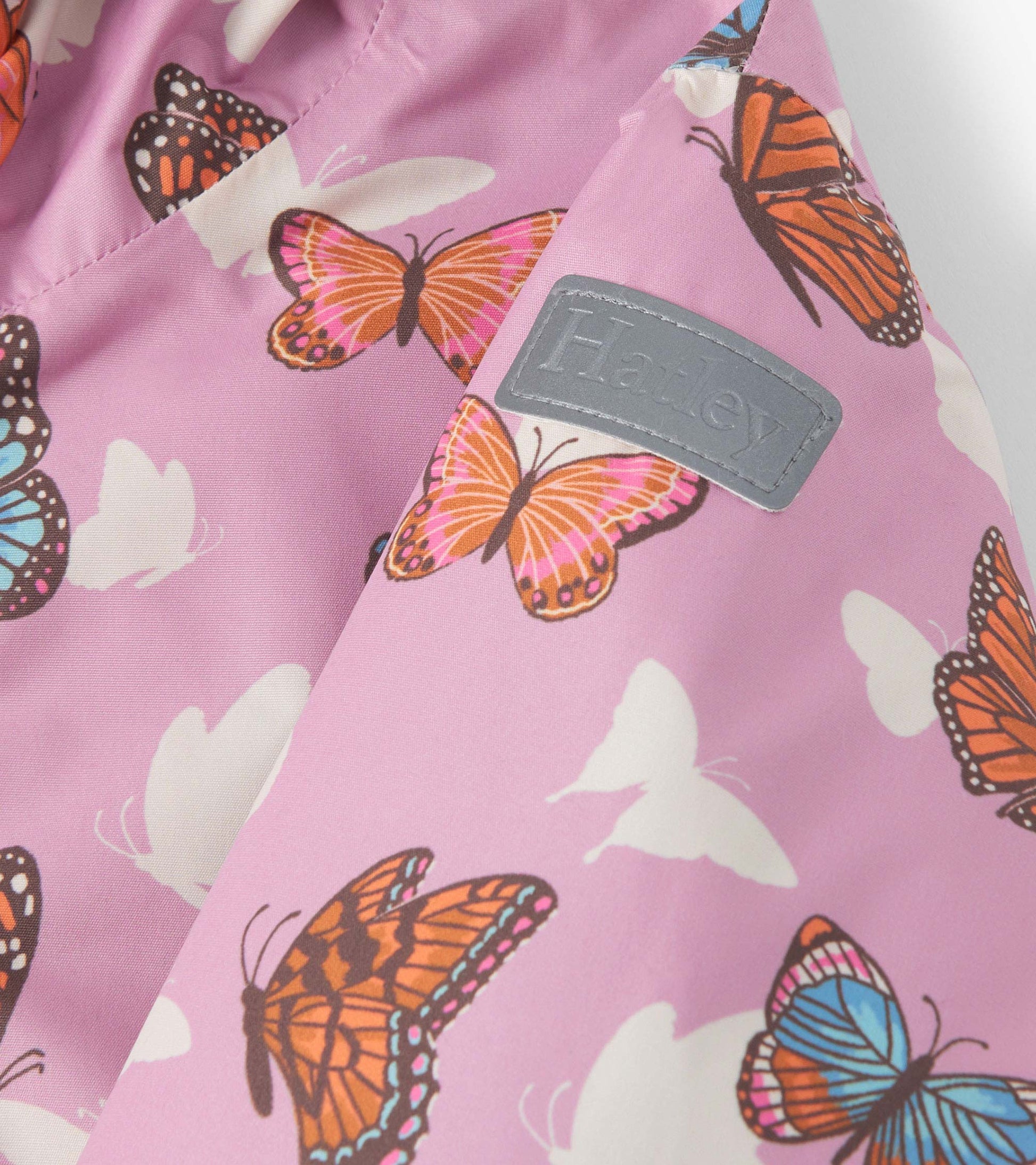 Lightweight zip-up rain jacket in pink with colorful butterfly patterns, perfect for girls.