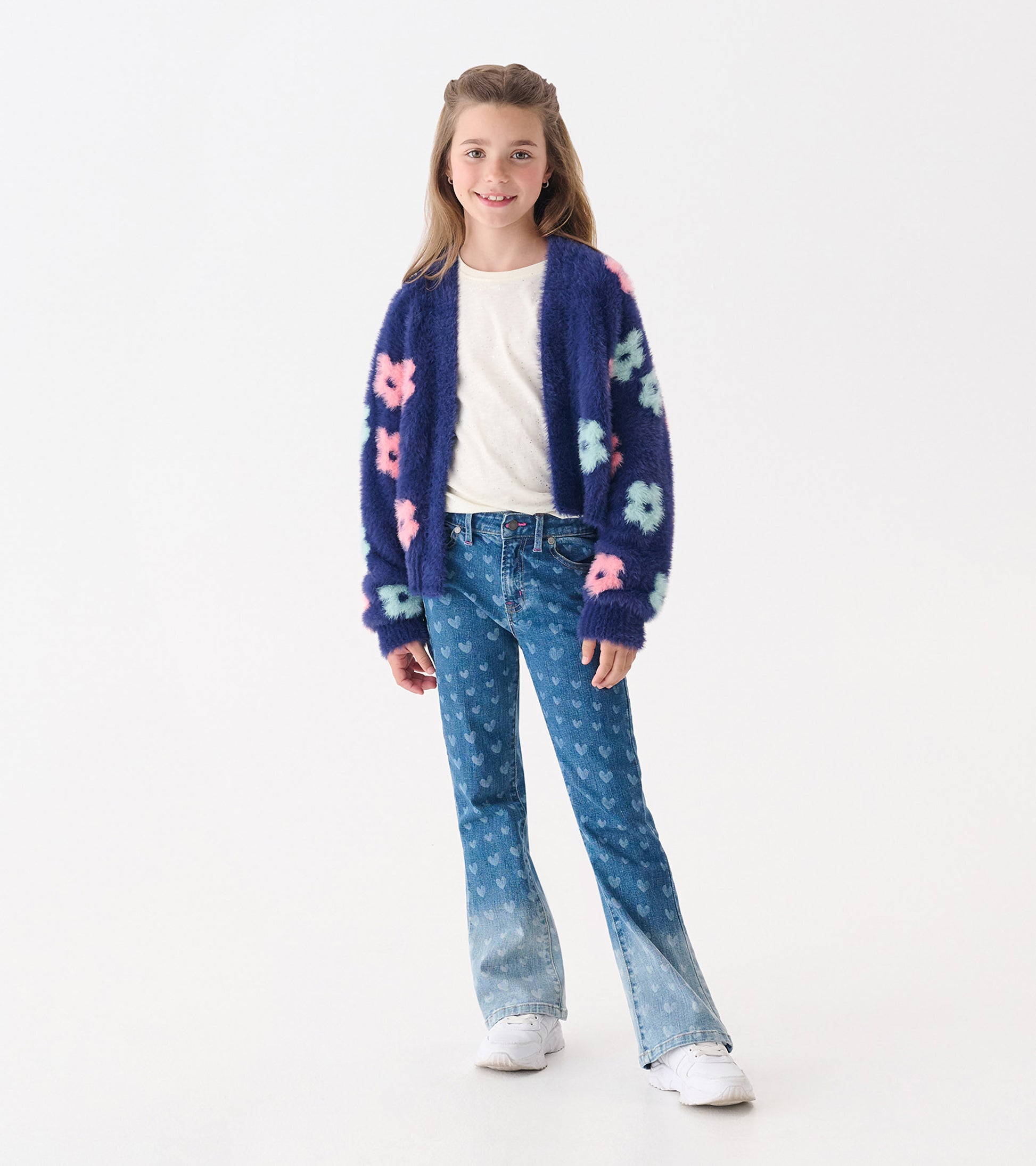 Navy open cardigan with large pink and blue flowers, worn over a white top and paired with flared jeans.