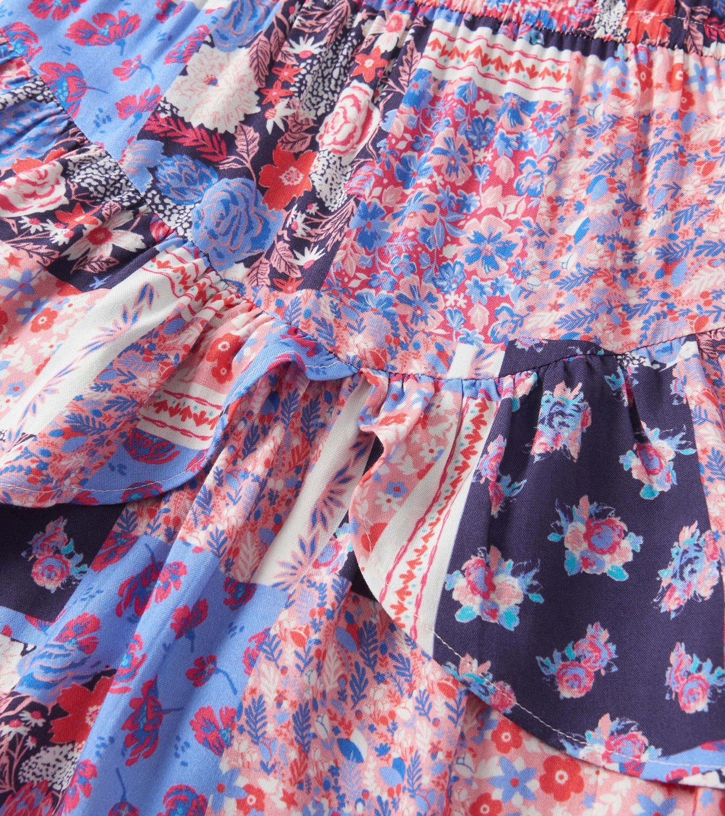 Colorful patchwork floral dress featuring ruffled flounce and a mix of blue, pink, and navy patterns.
