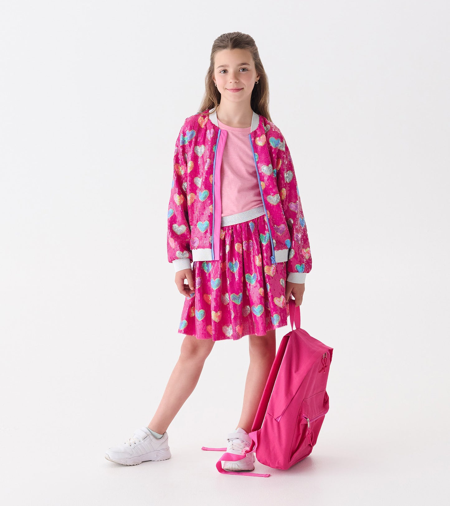 Pink sequin skirt with a heart pattern, featuring a flared shape, paired with a matching bomber jacket and white sneakers.