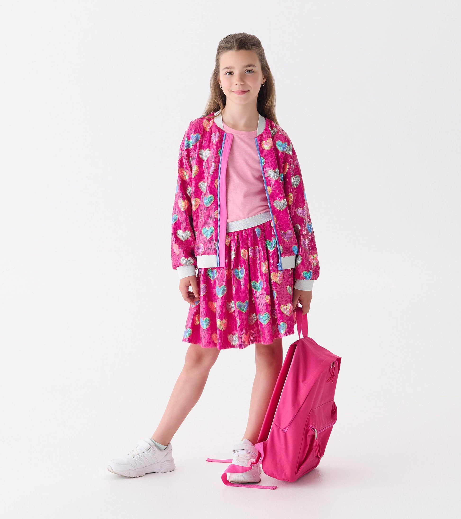 Pink sequin skirt with a heart pattern, featuring a flared shape, paired with a matching bomber jacket and white sneakers.