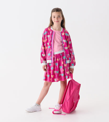 Pink sequin skirt with a heart pattern, featuring a flared shape, paired with a matching bomber jacket and white sneakers.