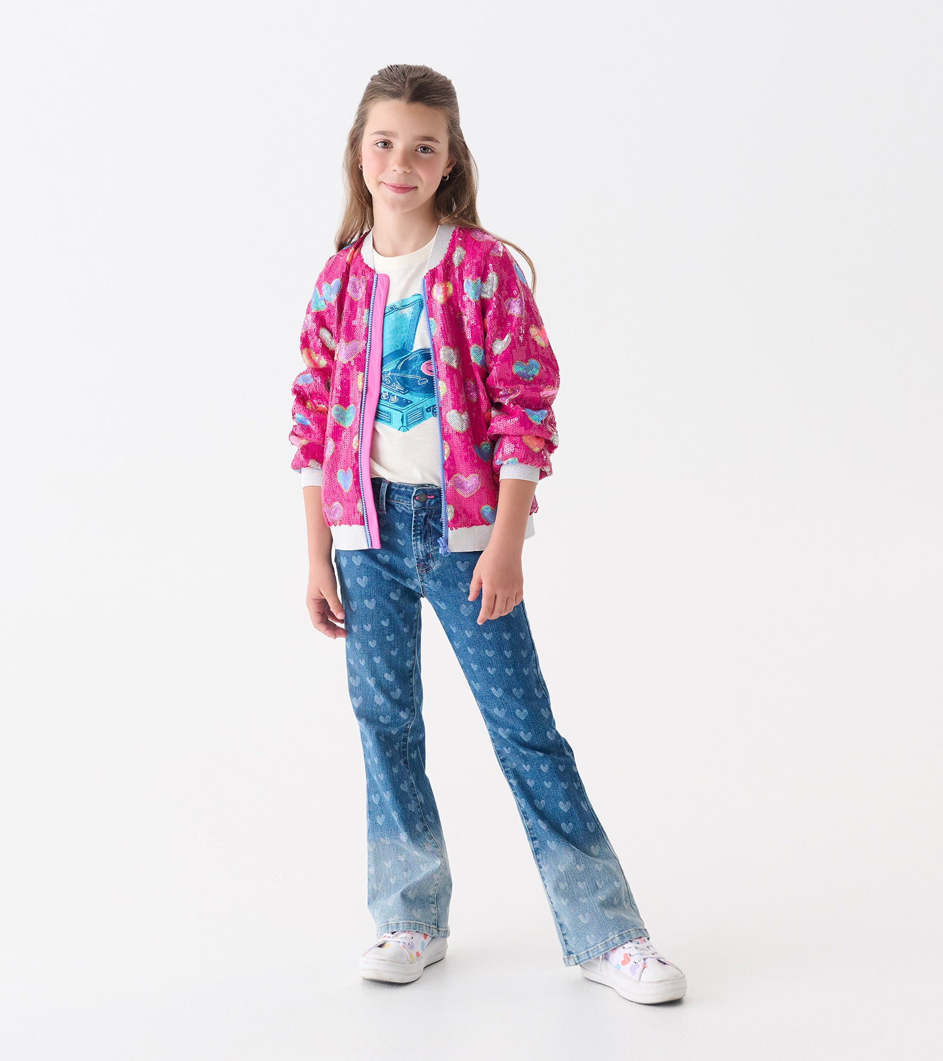 Pink bomber jacket with sequin heart pattern, featuring a front zipper and ribbed cuffs, worn over a graphic tee and jeans.