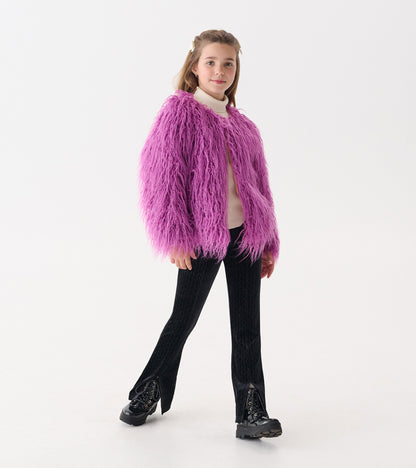 Purple Mongolian faux fur topper with long sleeves, worn over a light sweater and paired with black pants and boots.