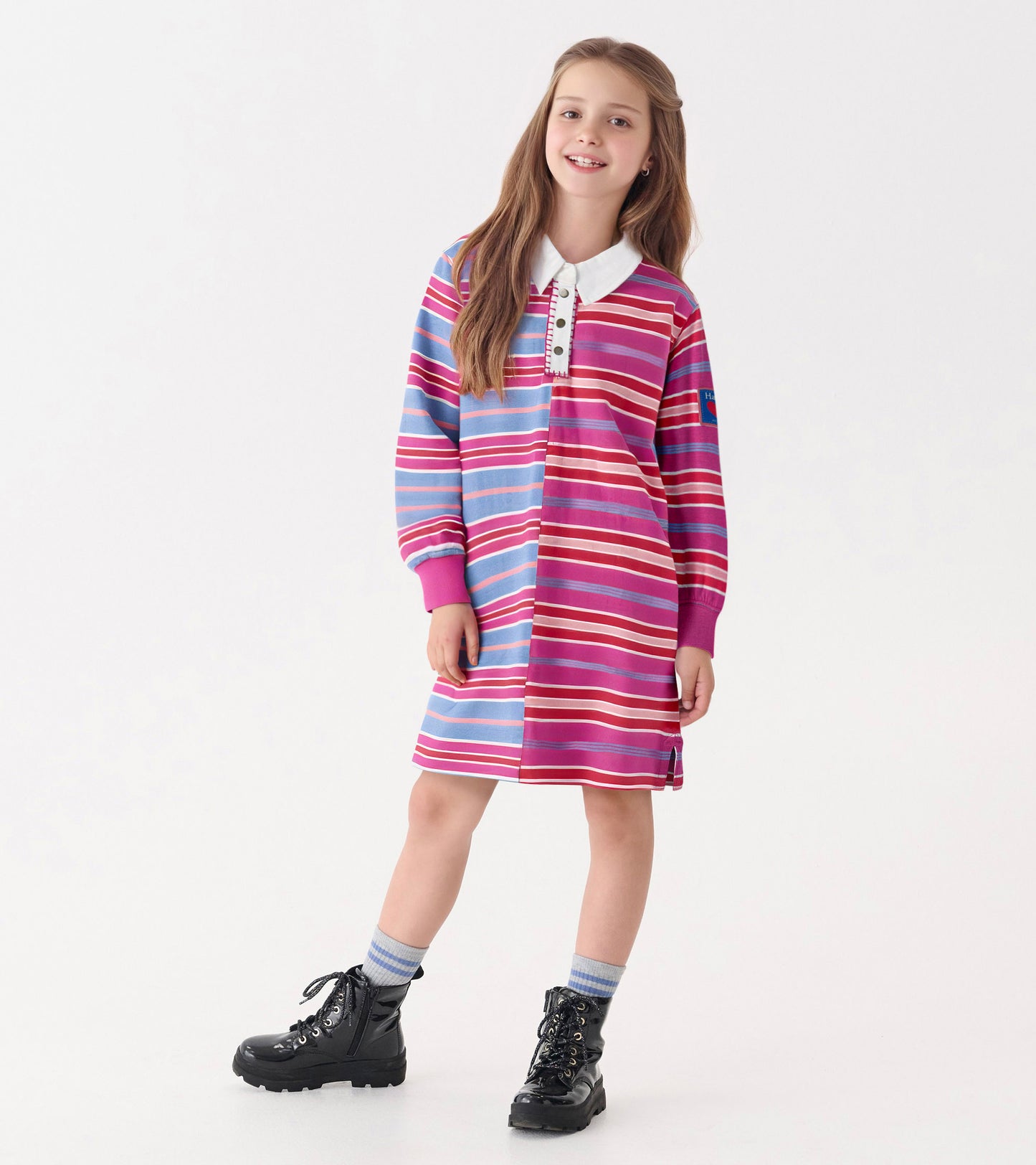 Colorful striped polo dress featuring pink, blue, and white stripes with a collar and long sleeves, styled with black boots.