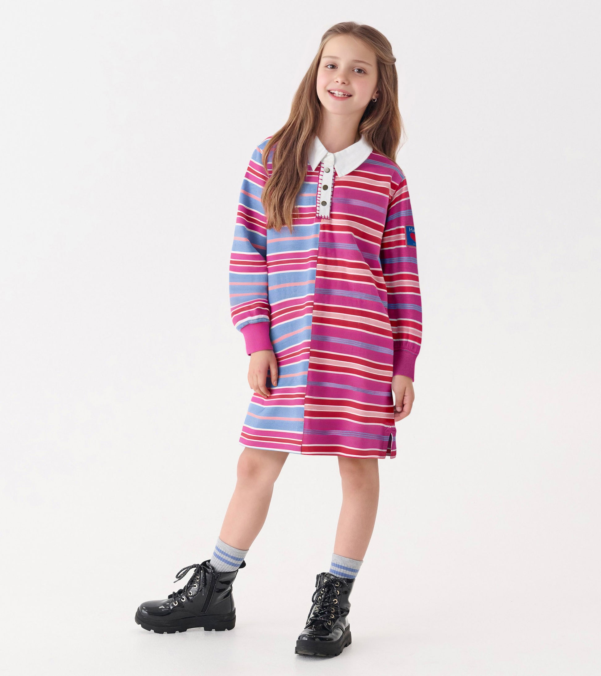 Colorful striped polo dress featuring pink, blue, and white stripes with a collar and long sleeves, styled with black boots.