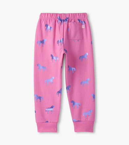 Pink cuffed track pants featuring a playful horse pattern in shades of blue, with an elastic waistband and a back pocket.